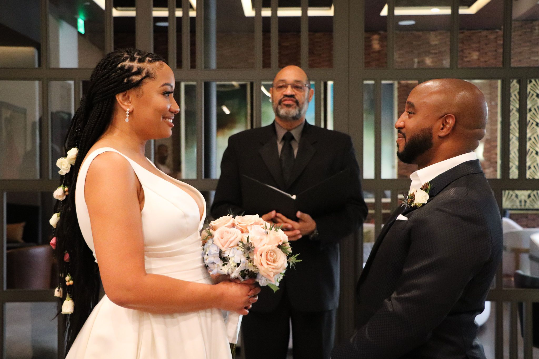 Wedding ceremony taking place in modern building interior with officiant and couple exchanging vows.