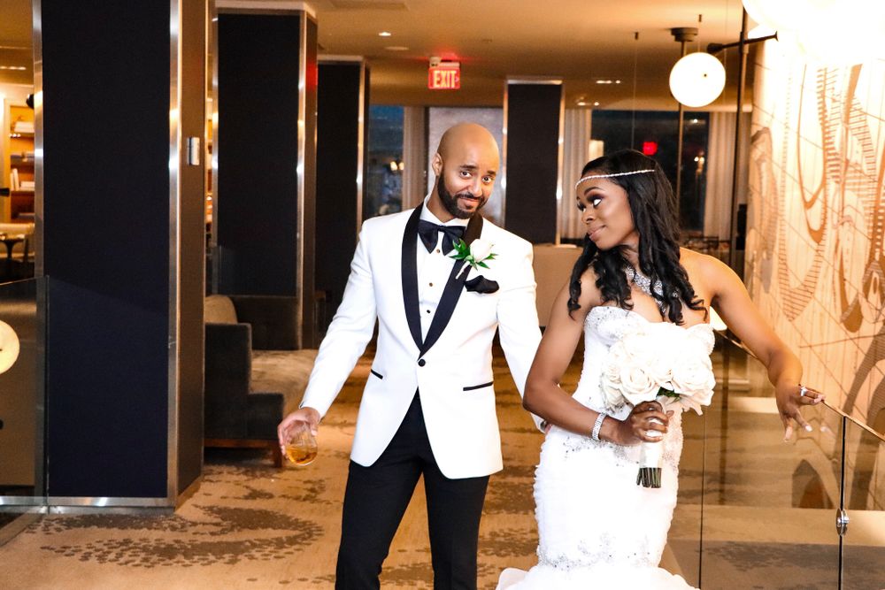 A couple in formal white and black attire dancing in an elegant hotel hallway.
