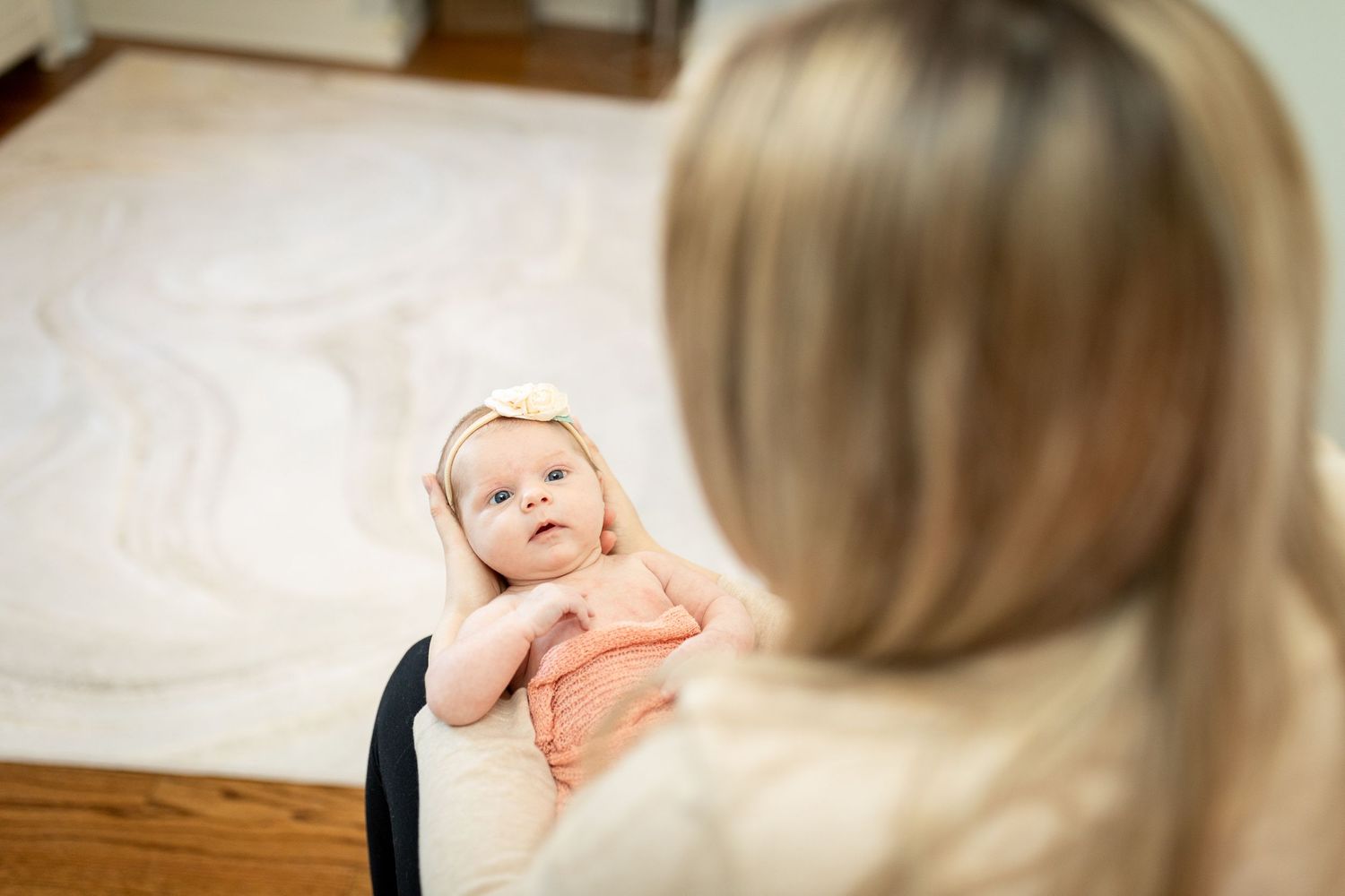 Gentle interaction between caregiver and baby in light-filled room.