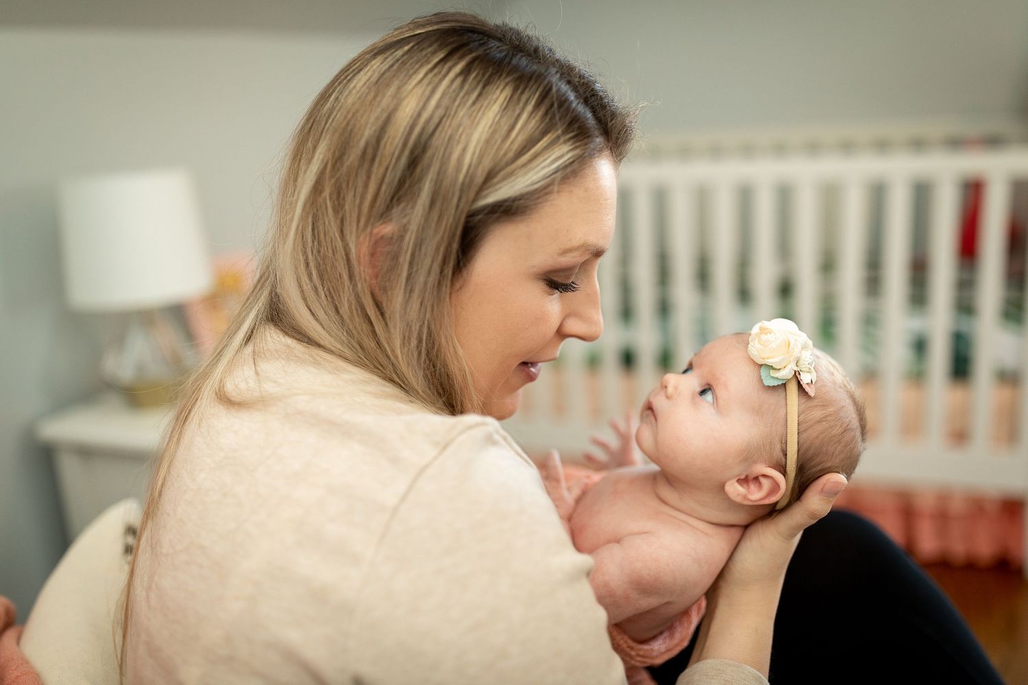 Intimate bonding moment between caregiver and infant in white nursery setting.