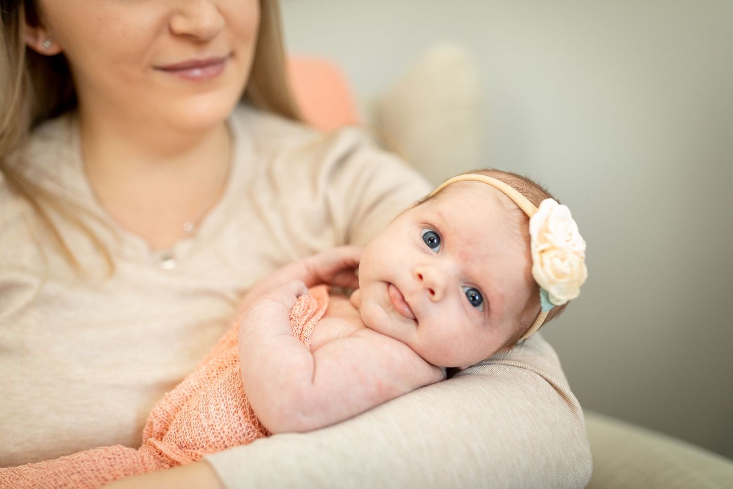 Baby wearing peach outfit looks up during tender moment.