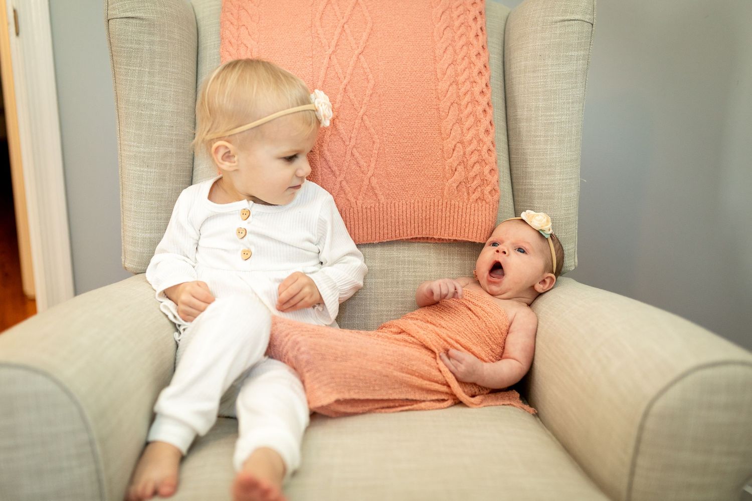 Comfortable beige armchair with coral throw pillow in a cozy corner reading nook.