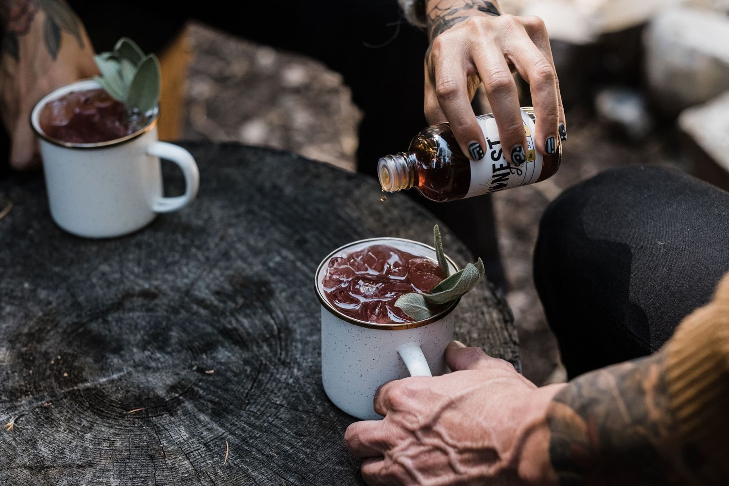 Hands preparing coffee and drinks on a dark surface with moody lighting.