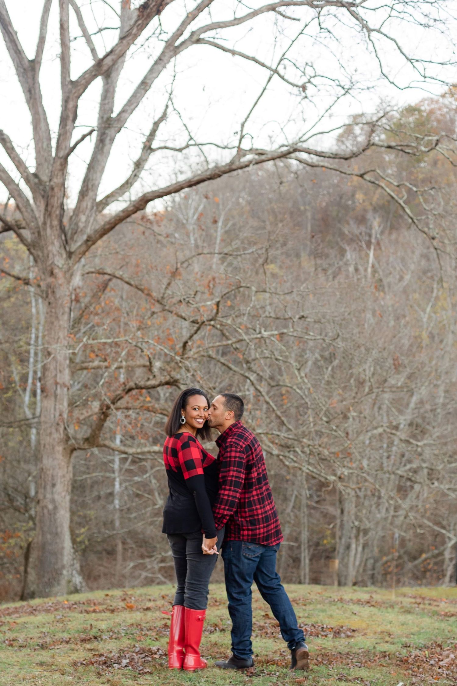 A rustic fall engagement photo setting with bare trees and autumn colors.