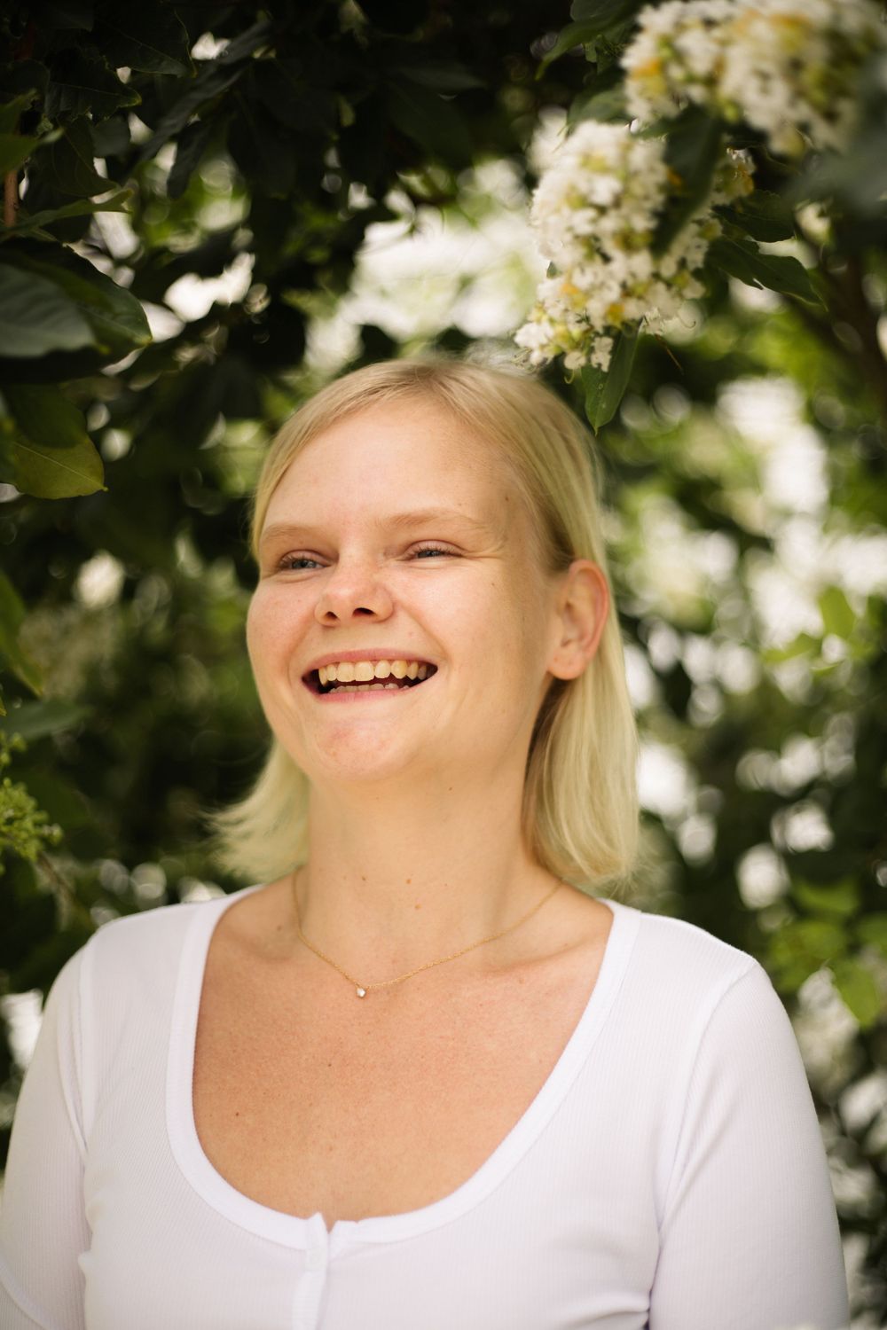 Joyful outdoor portrait with white flowering branches and natural sunny lighting.