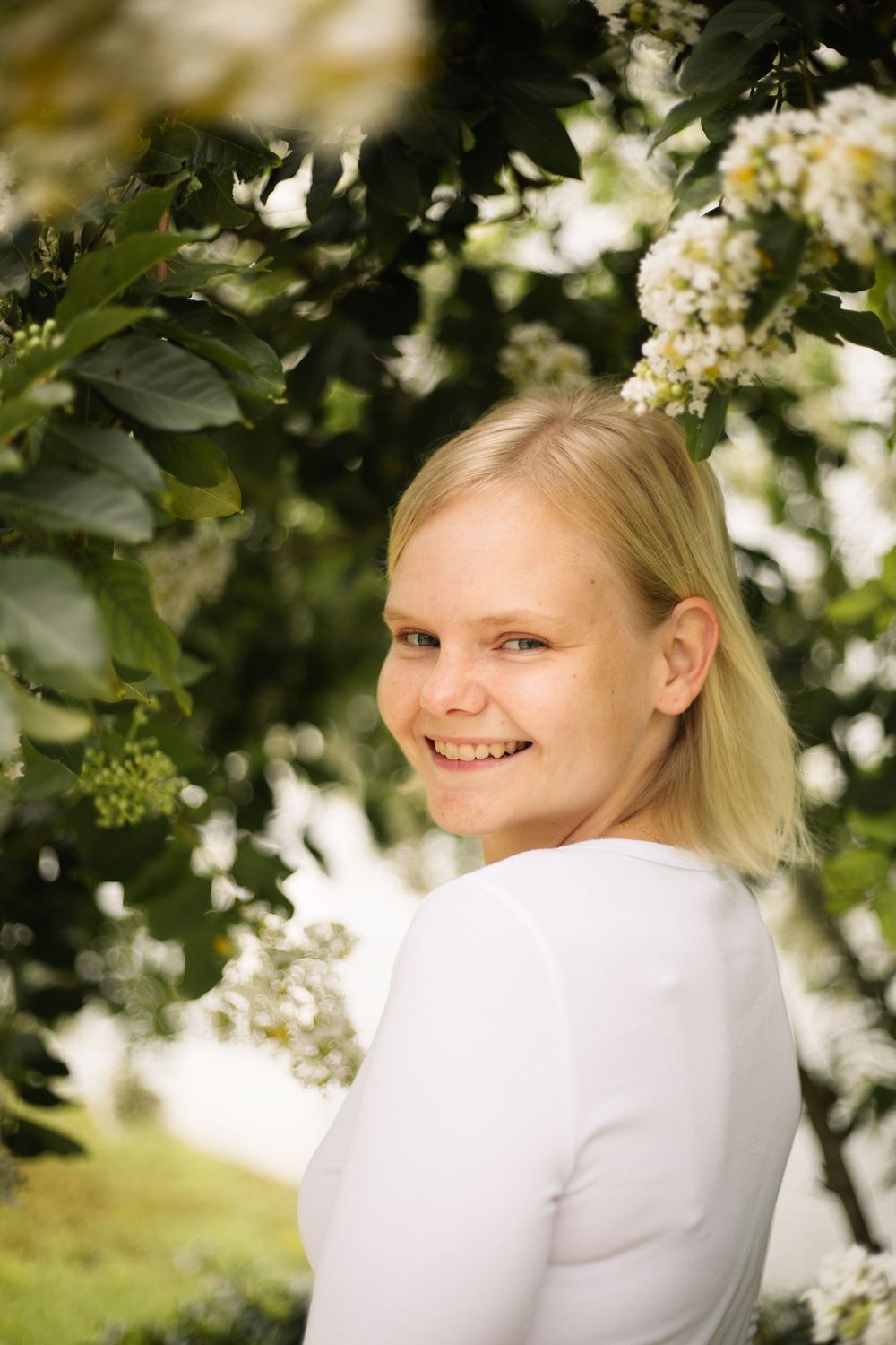 Casual outdoor portrait with white flowering tree and soft natural lighting.