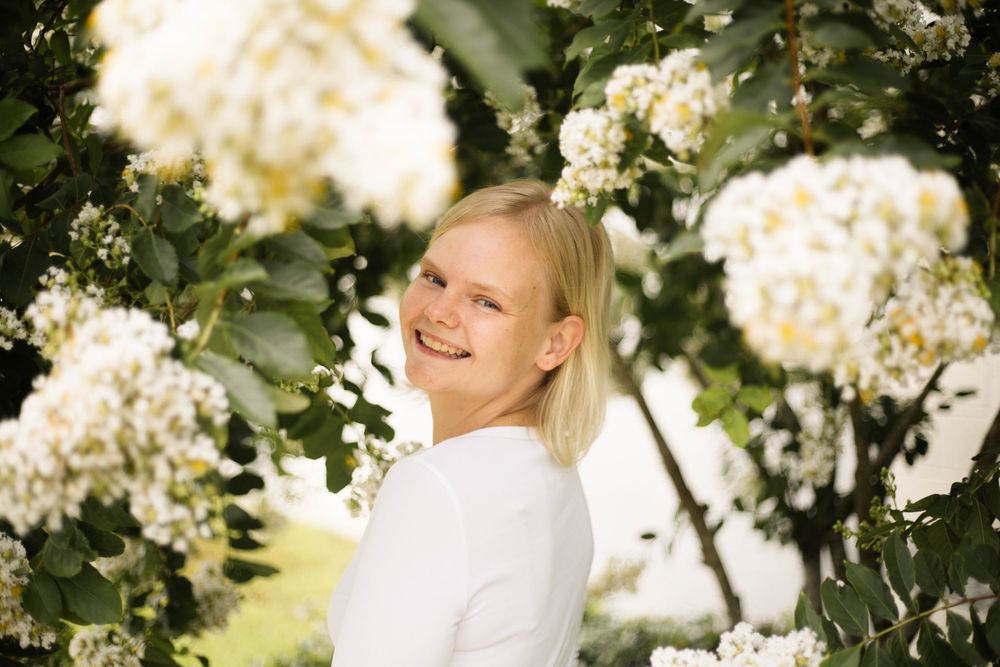 Outdoor portrait with white flowering branches and warm lighting creating a cheerful atmosphere.