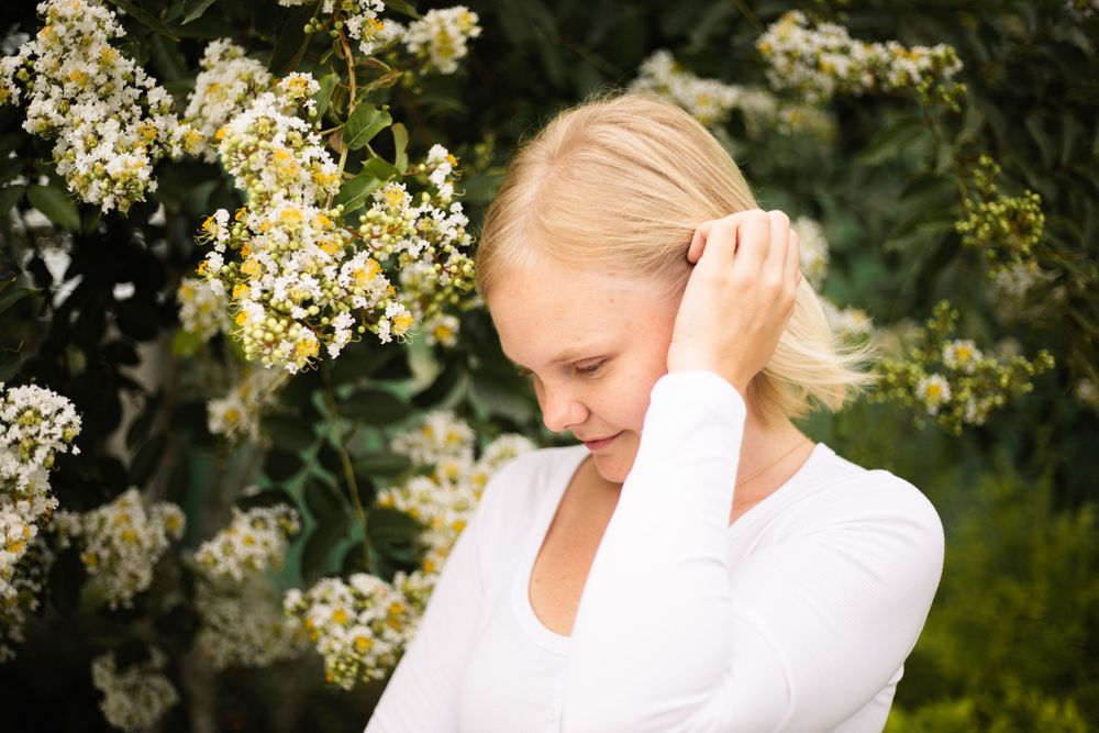 Natural portrait with gentle hand gesture among flowering branches.