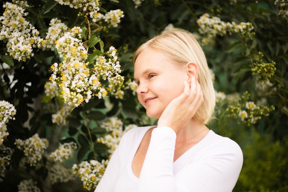 Artistic portrait with delicate hand placement among blooming spring flowers.