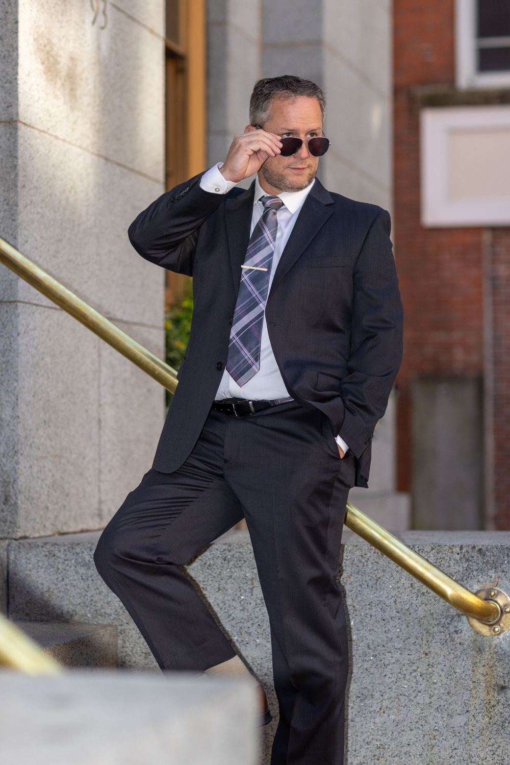 Person in business suit sliding down handrail in playful pose.