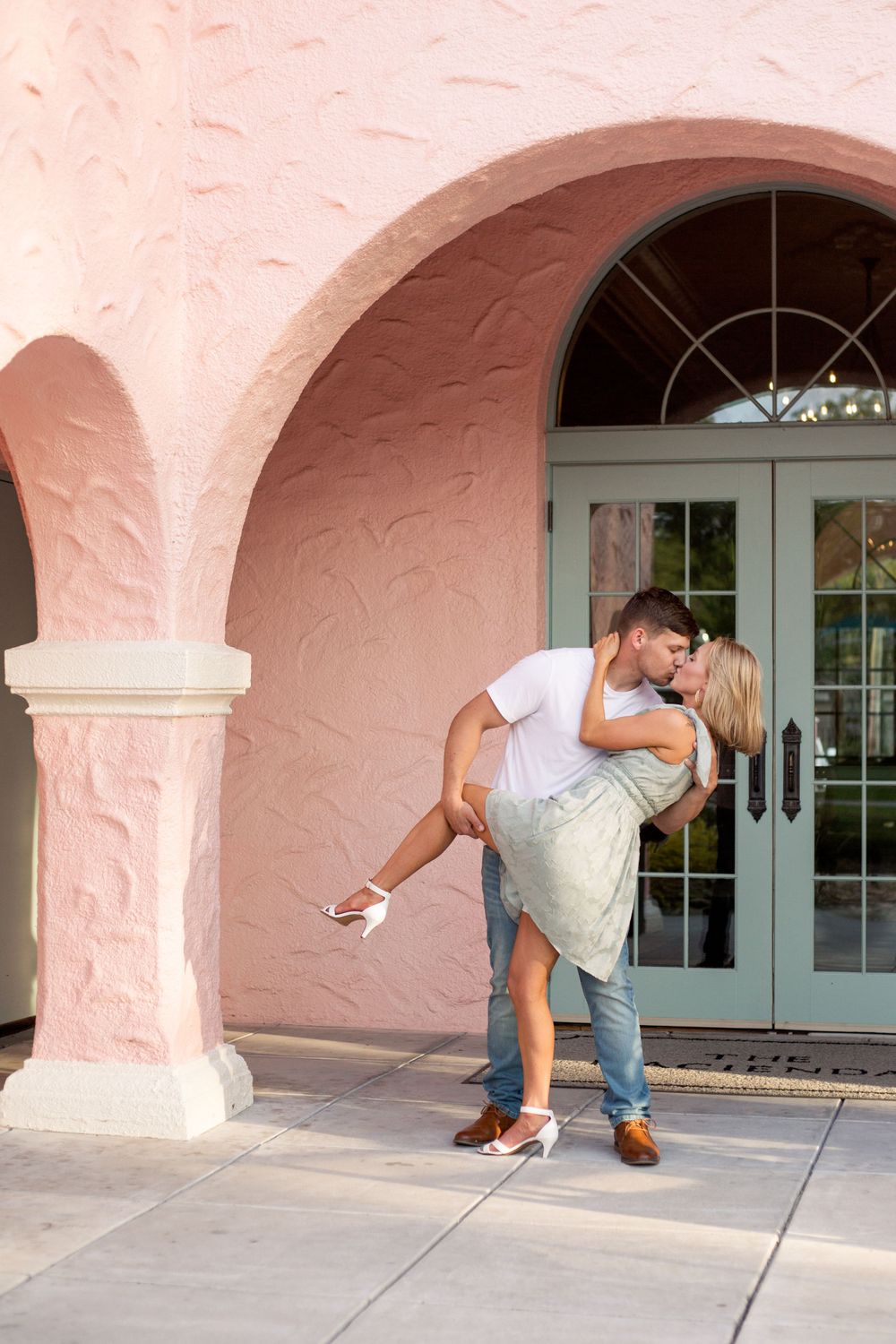 Couple sharing a romantic dip pose in front of an arched doorway.