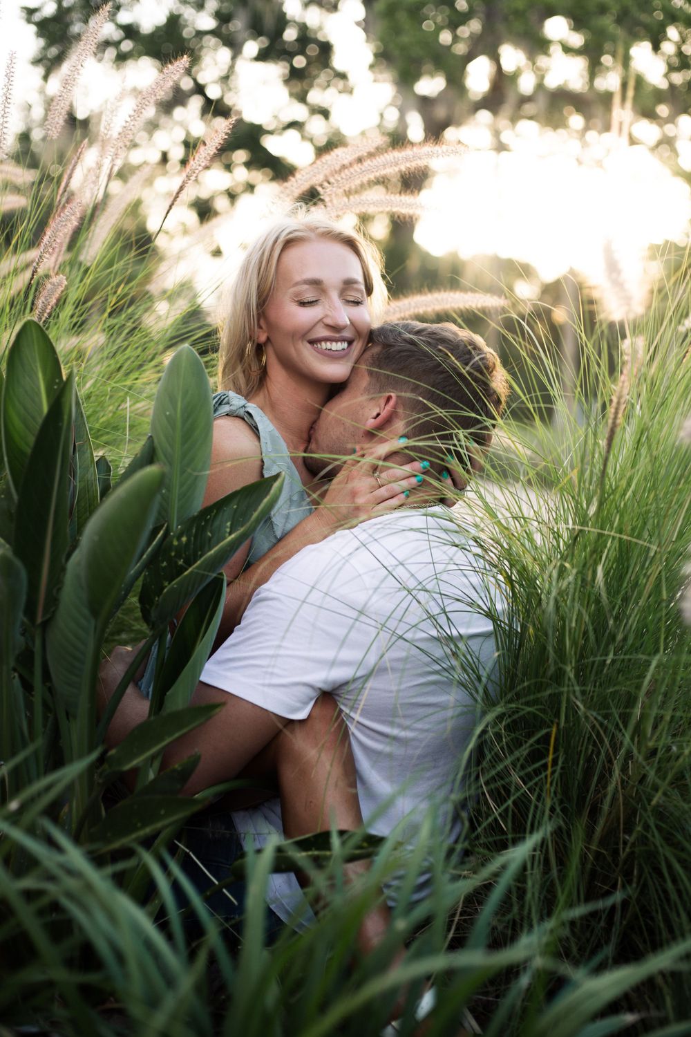 Joyful romantic moment between couple surrounded by tall grass and greenery.