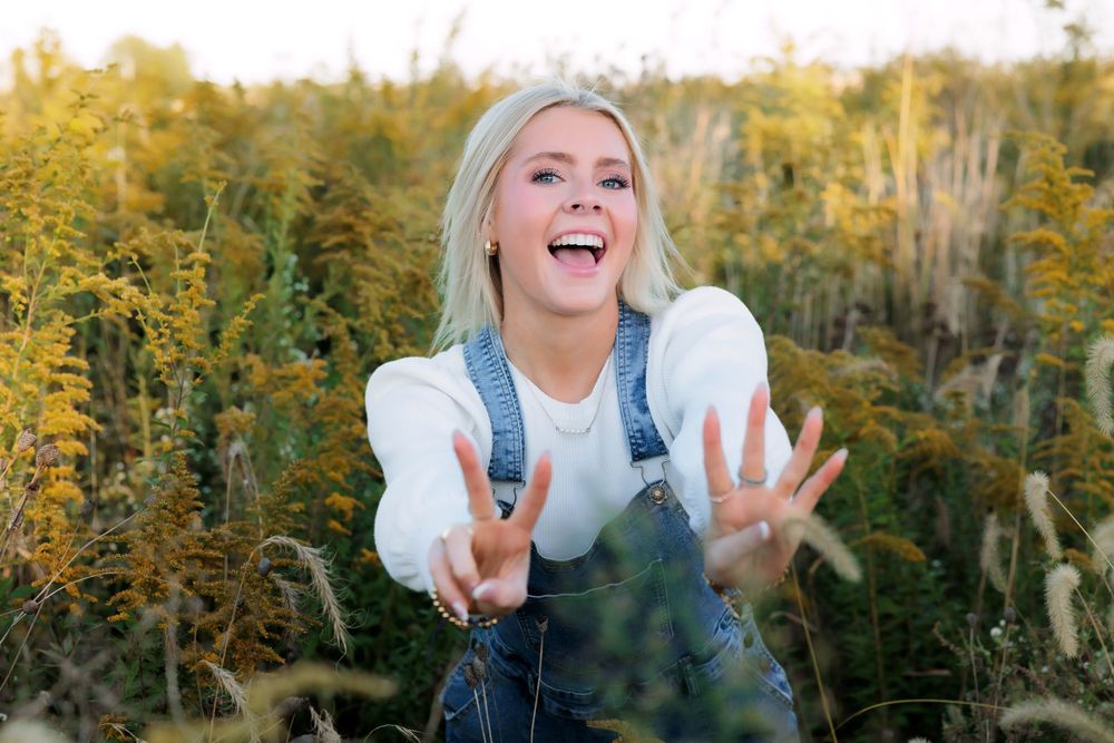 Energetic outdoor portrait with expressive hand gestures in denim overalls.