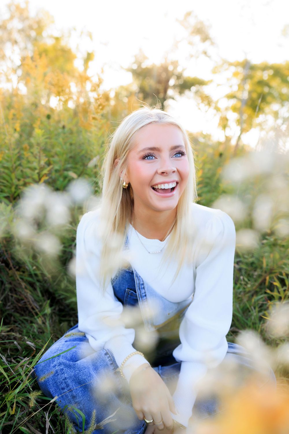 Candid outdoor portrait in white sweater among wildflowers during golden hour.