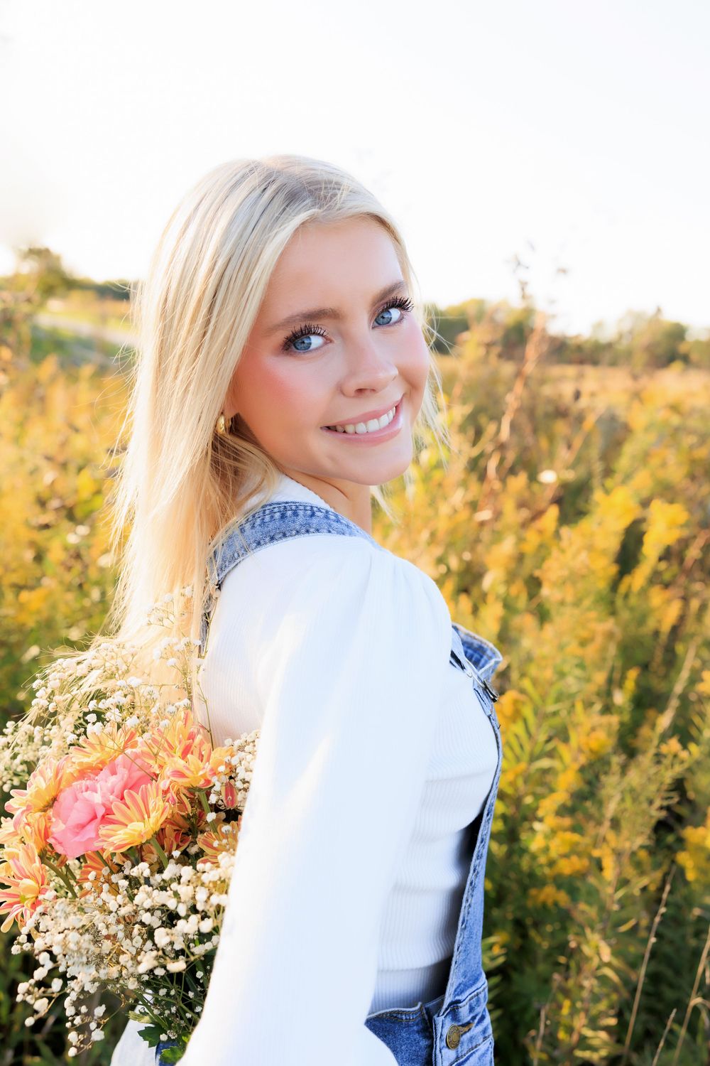 Summer portrait with wildflower bouquet against a golden field at sunset.