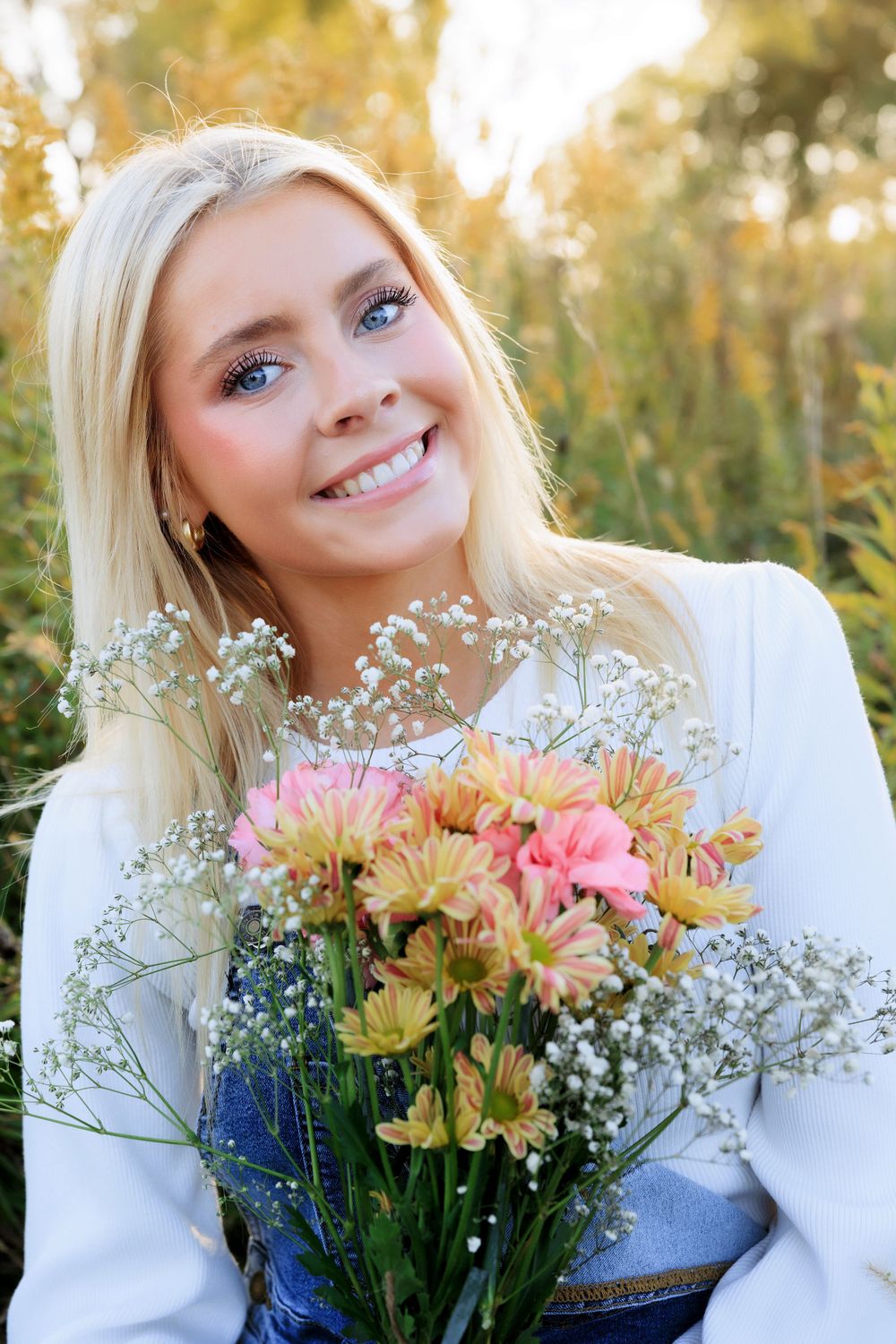 Close-up portrait with a delicate bouquet of pink and yellow flowers in natural outdoor lighting.
