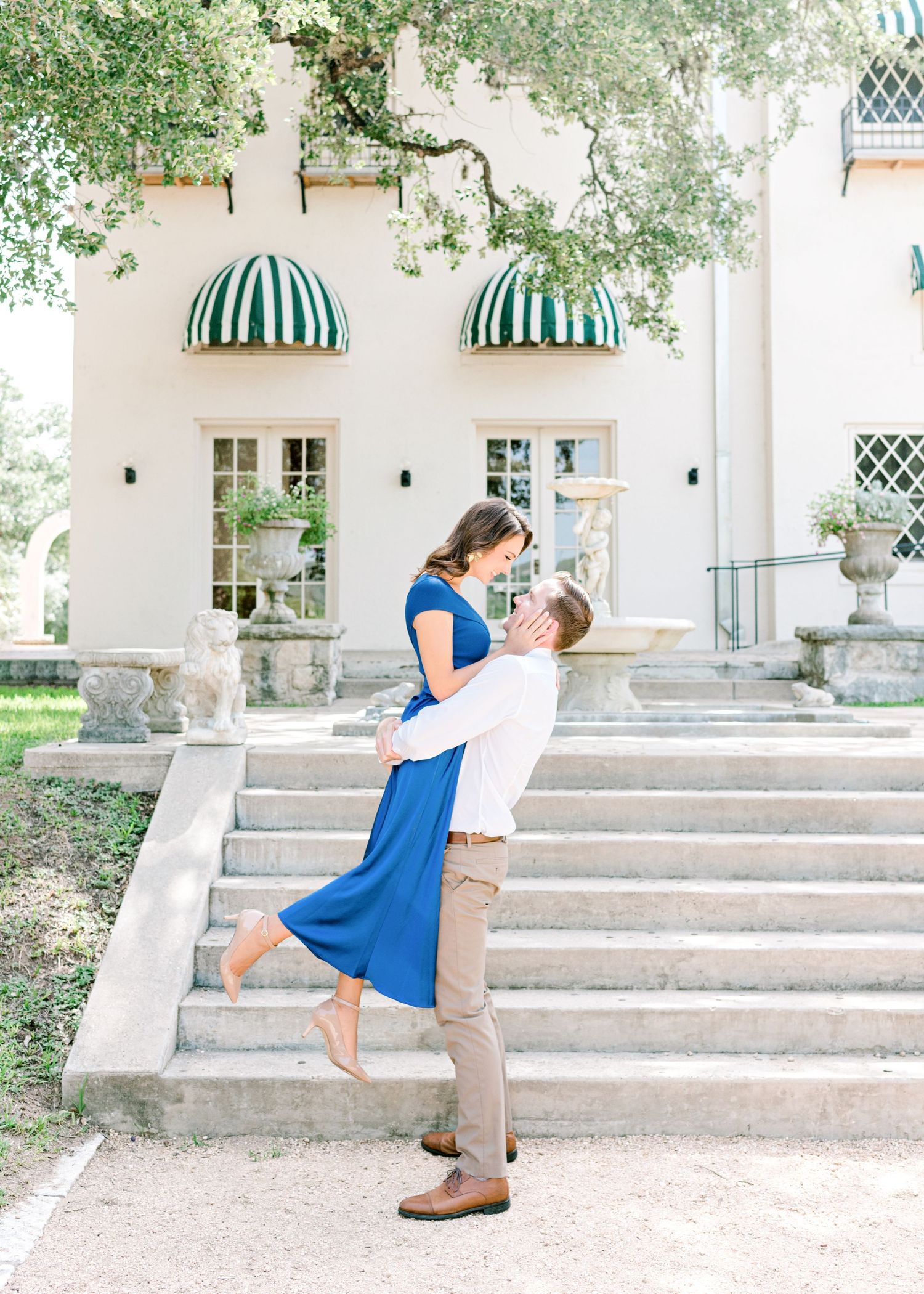 husband lifting his wife up as her hand rests on his cheek at Laguna Gloria in Austin, TX.