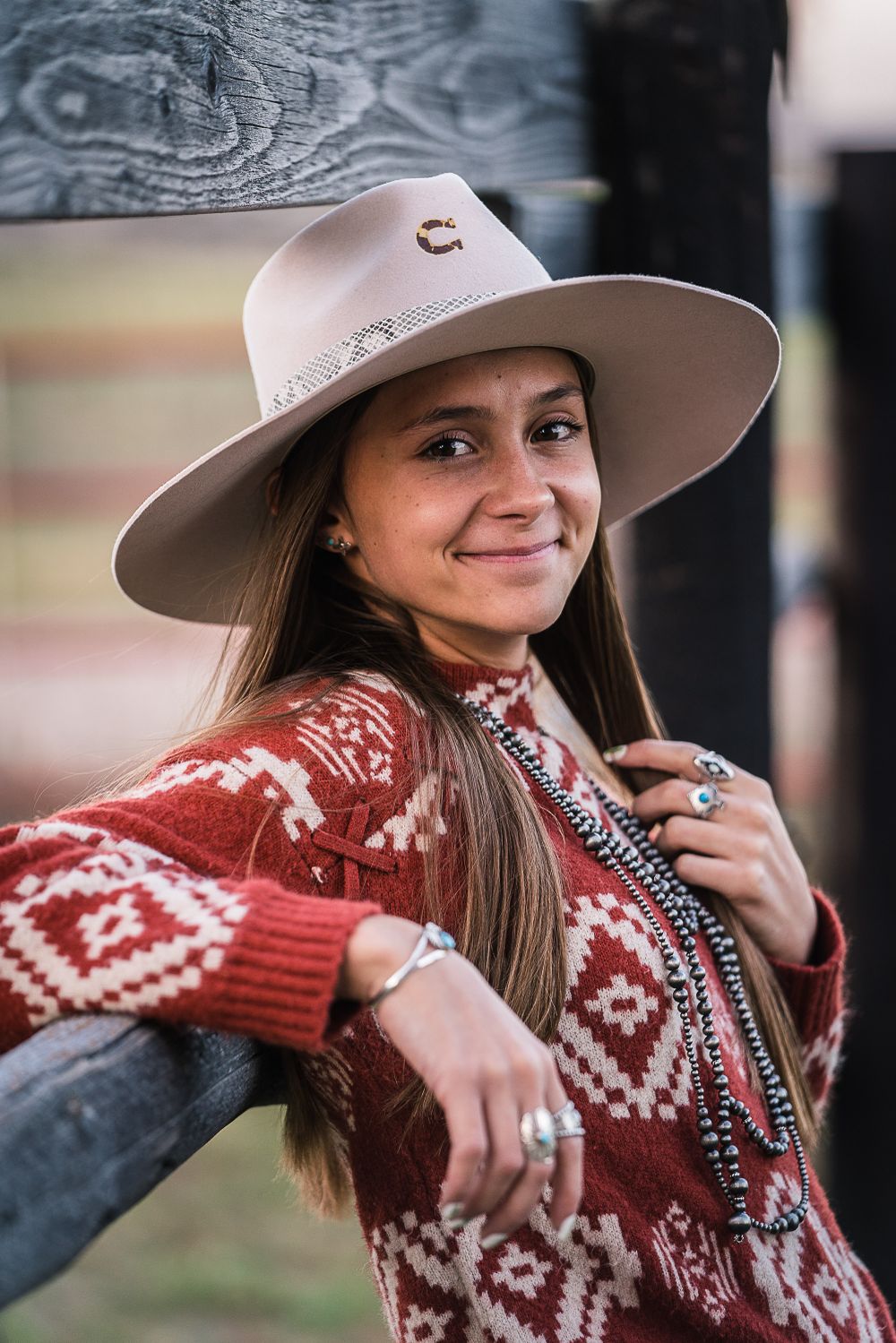 Western style portrait featuring red patterned sweater and wide brim hat.