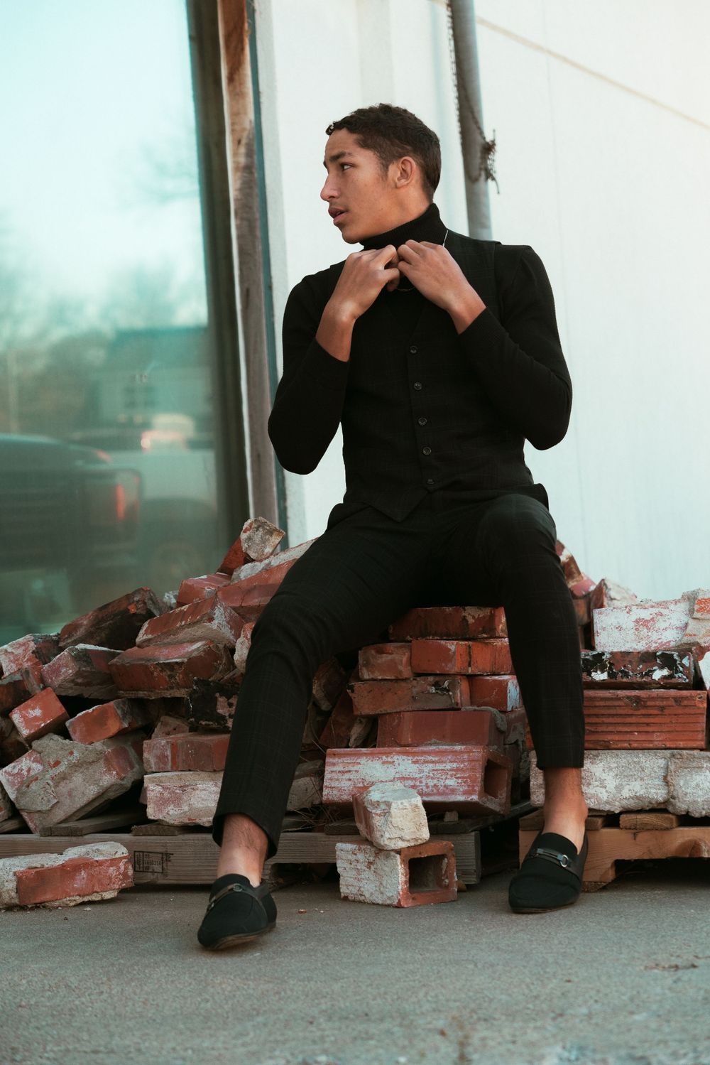 A sequence of dramatic poses against a brick wall showing emotion and contemplation in black attire.