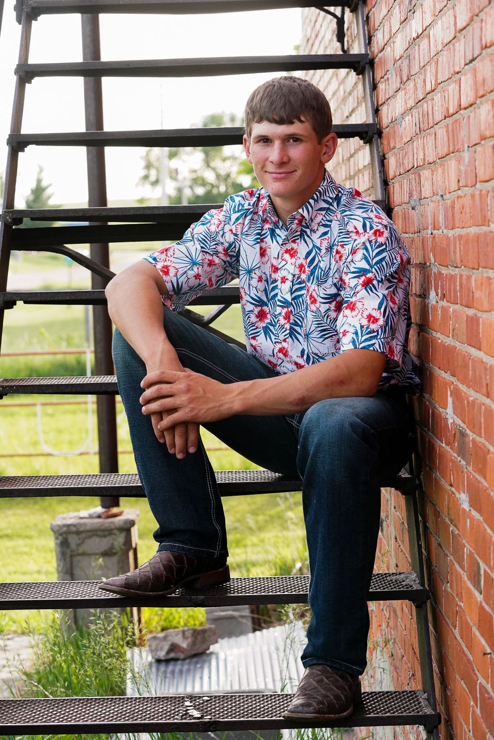 Casual portrait on rustic brick steps with floral print shirt.