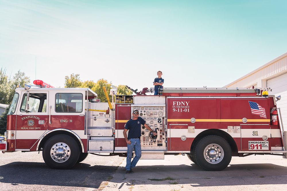 A series of red fire trucks lined up in a row against a bright sky.