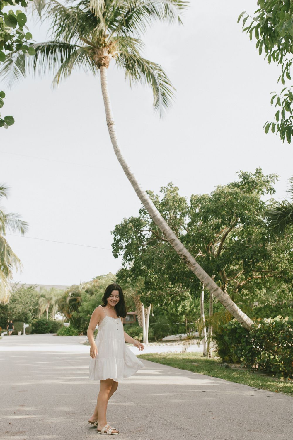 Lifestyle and fashion photo portrait of girl in tropical street with a dress