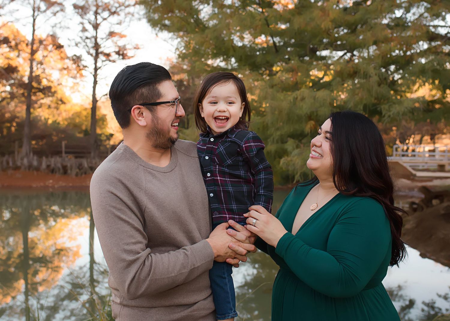 Joyful outdoor family portrait by lake during golden hour.