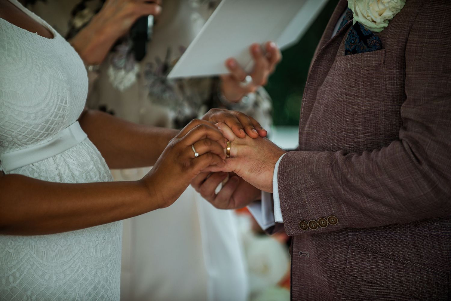 Close-up of hands exchanging rings during a wedding ceremony.