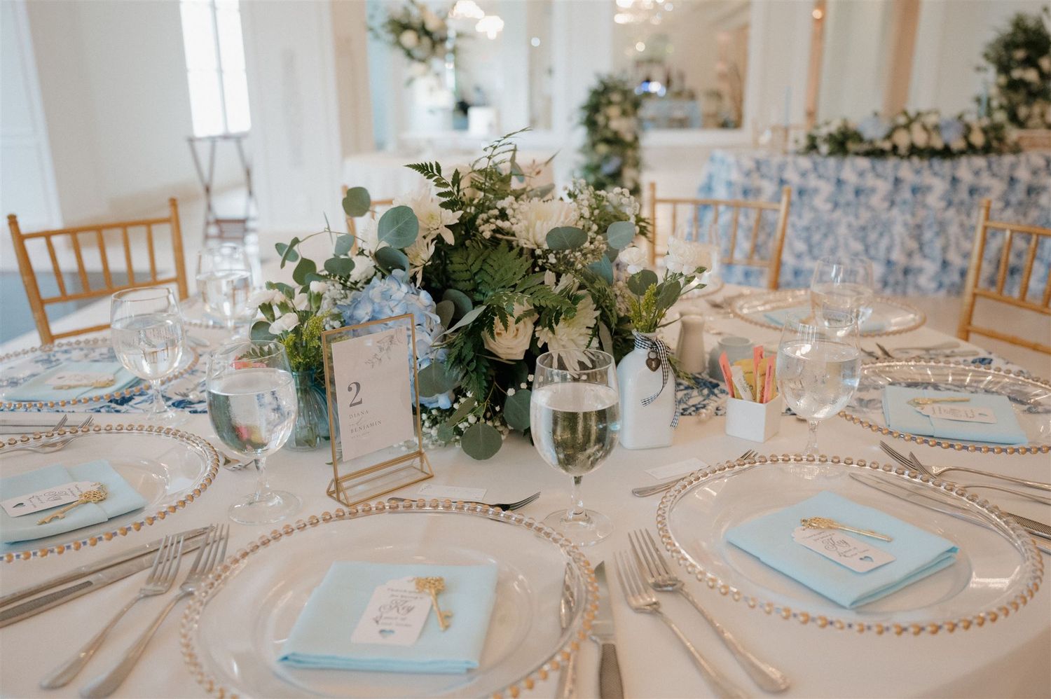 Elegant table setting with blue and white decor, crystal charger plates and floral centerpieces.