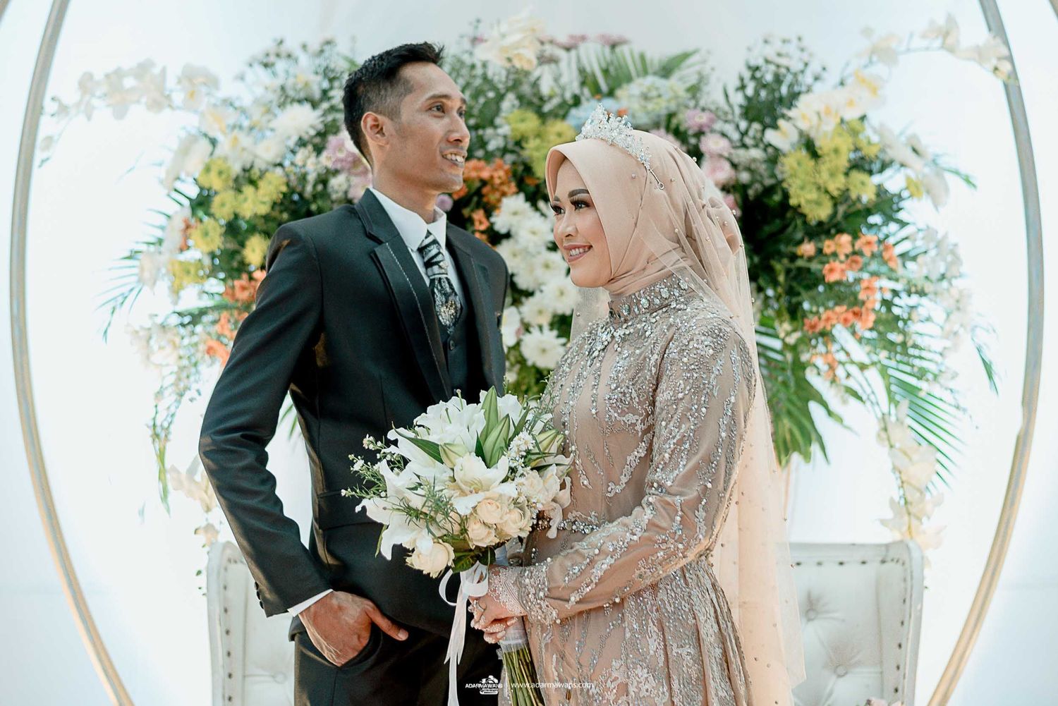 Couple posing at their wedding ceremony beneath an ornate floral arch.