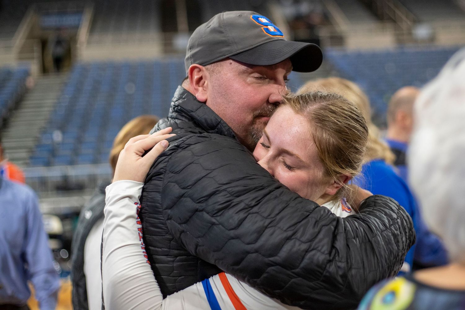 Emotional embraces and celebrations between athletes and coaches in an indoor sports venue.