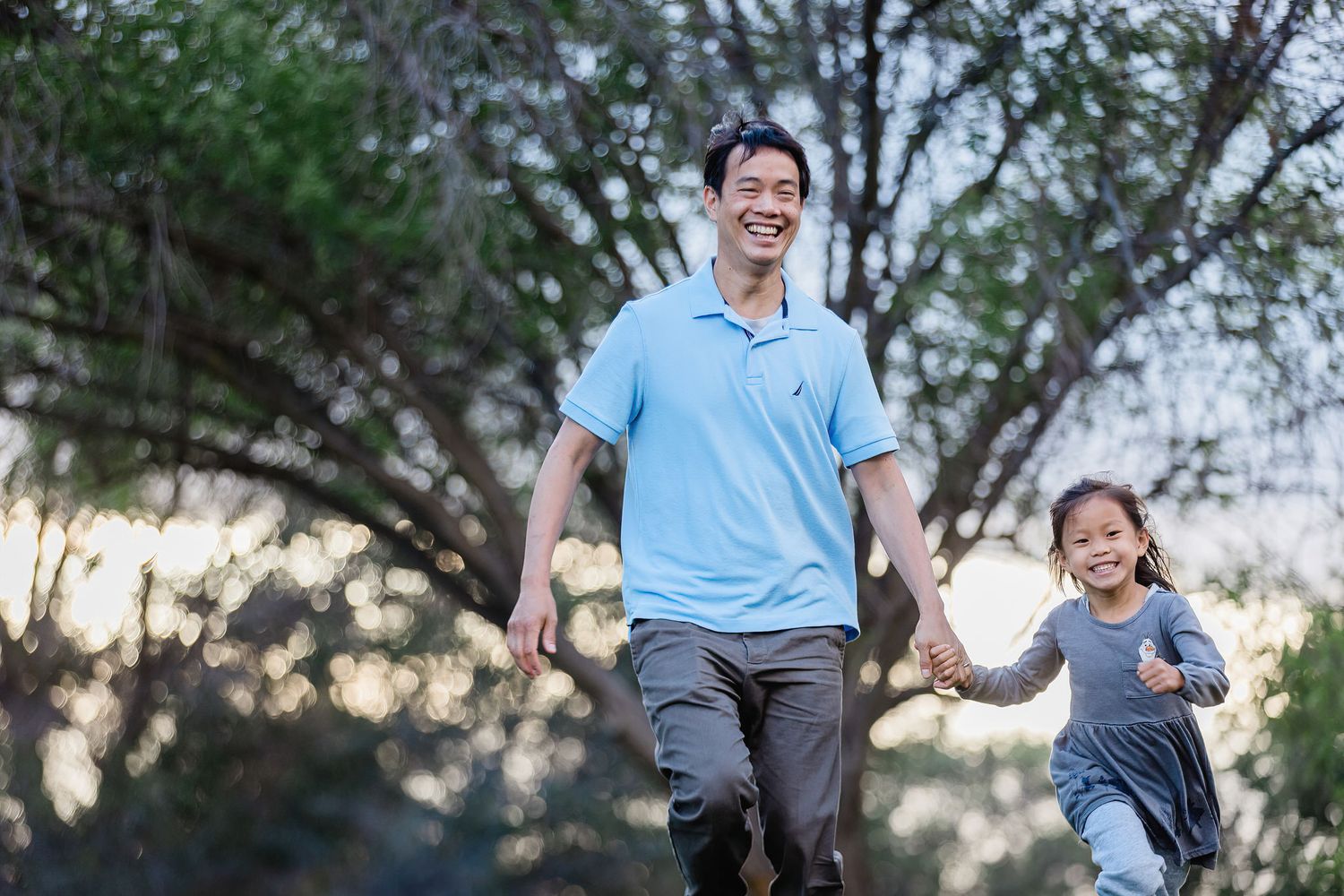 People jumping and playing together outdoors with trees in the background at dusk.