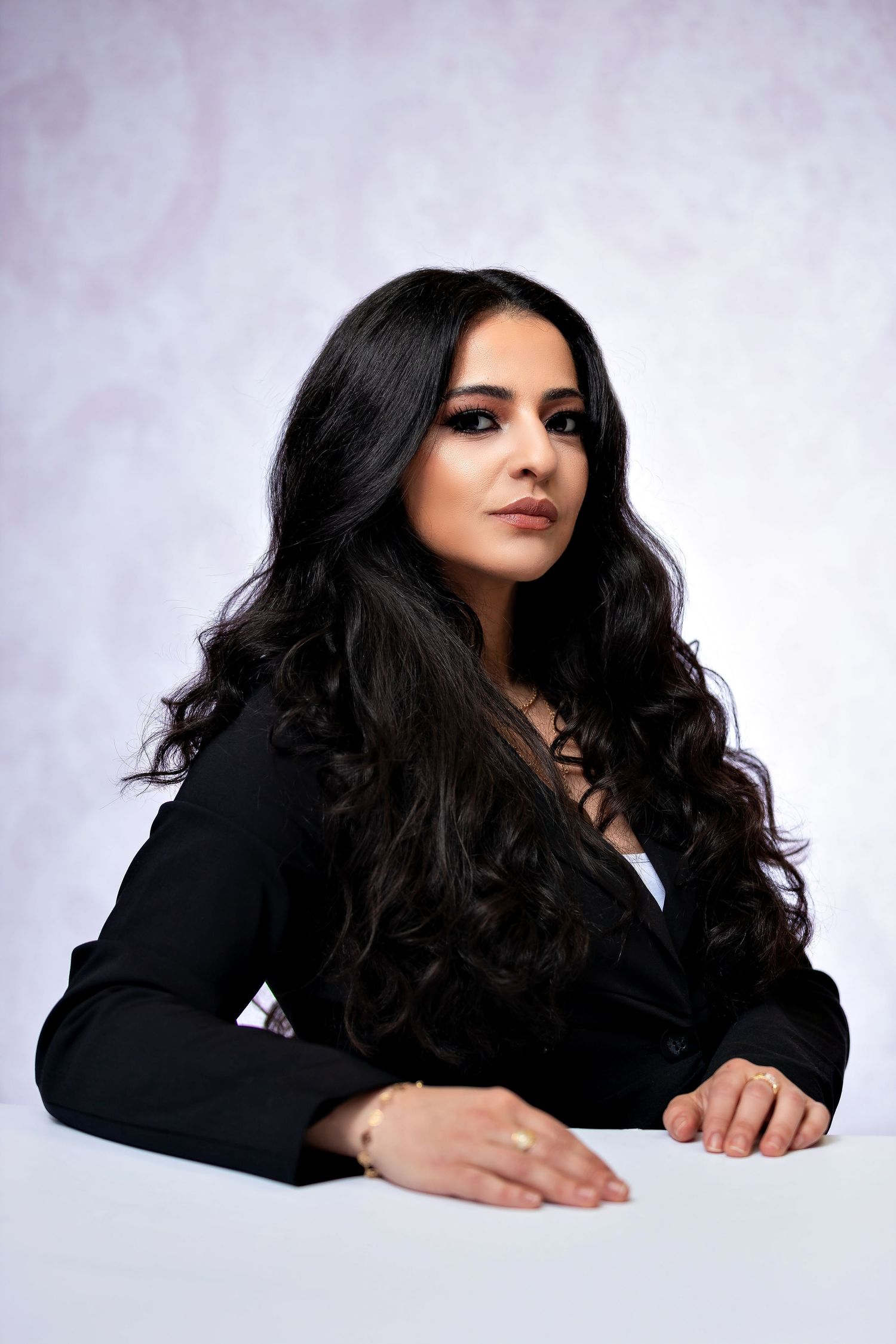 Professional studio portraits featuring dark-haired model in black blazer against light backdrop.