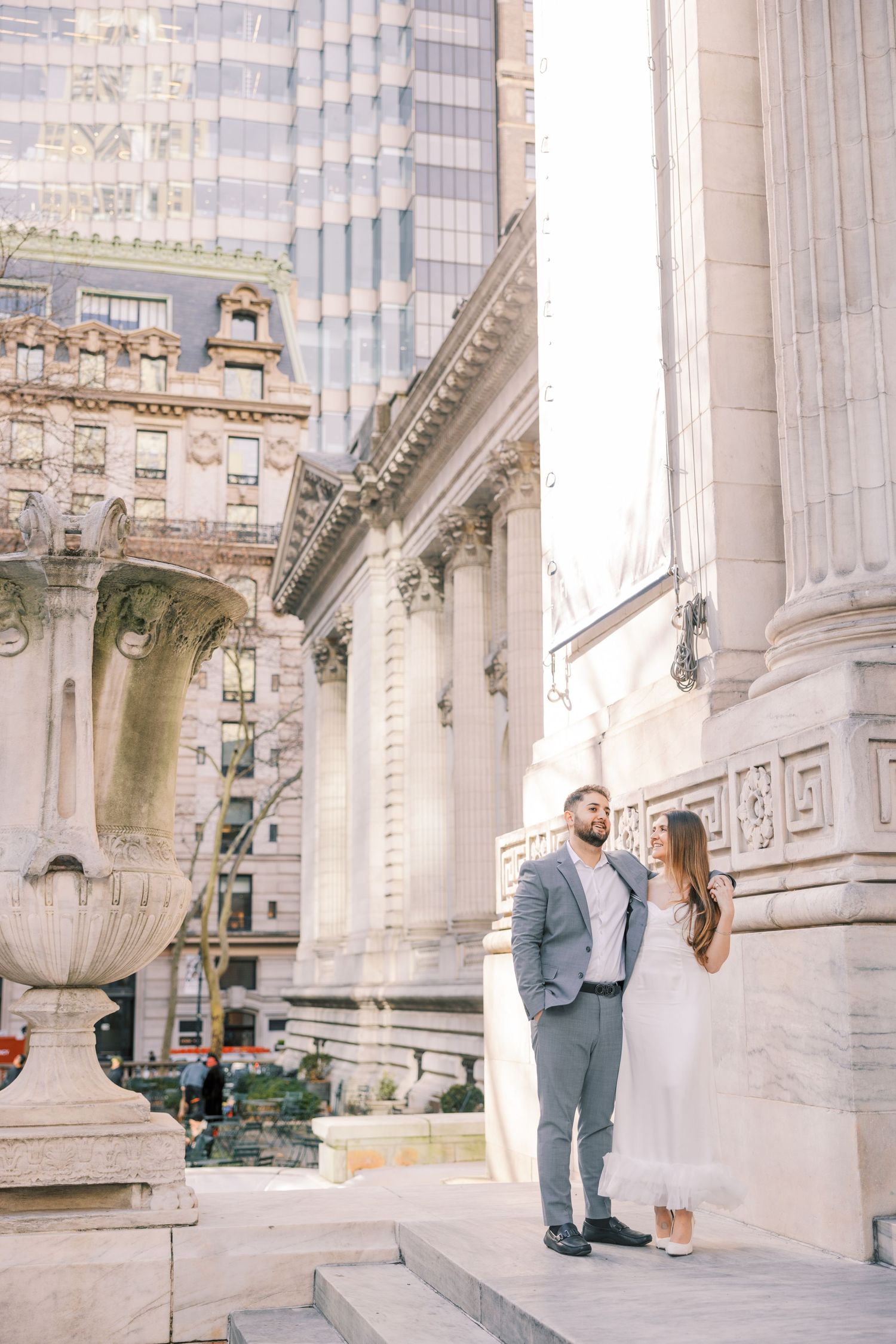 Couple sharing romantic moment on steps of grand neoclassical building with ornate stone columns.