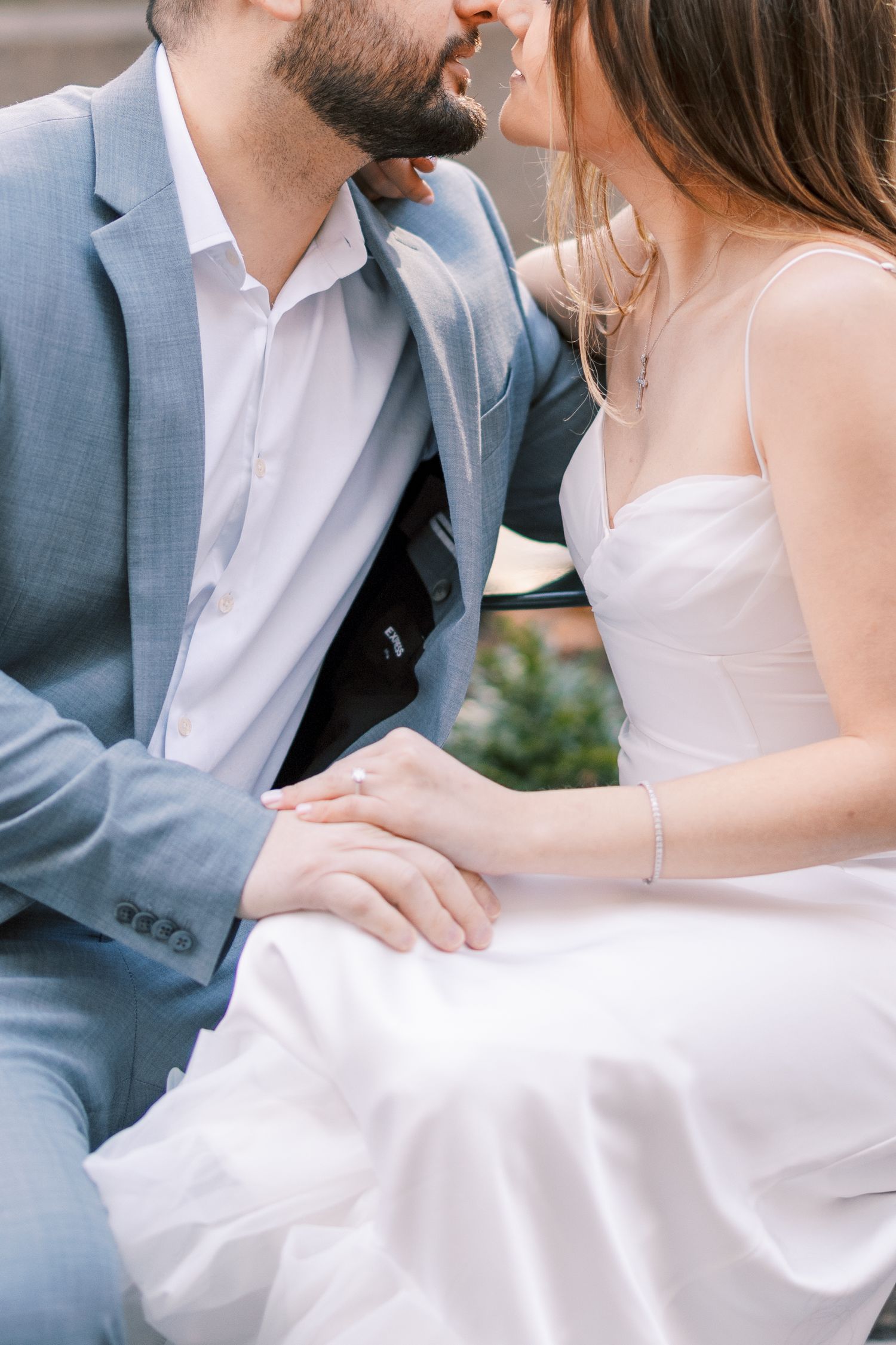 Close-up of couple nearly kissing while holding hands in wedding attire.
