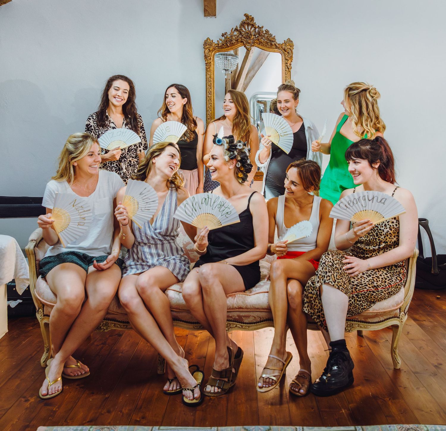 A group of wedding guests share laughs while seated together in a bright indoor setting.