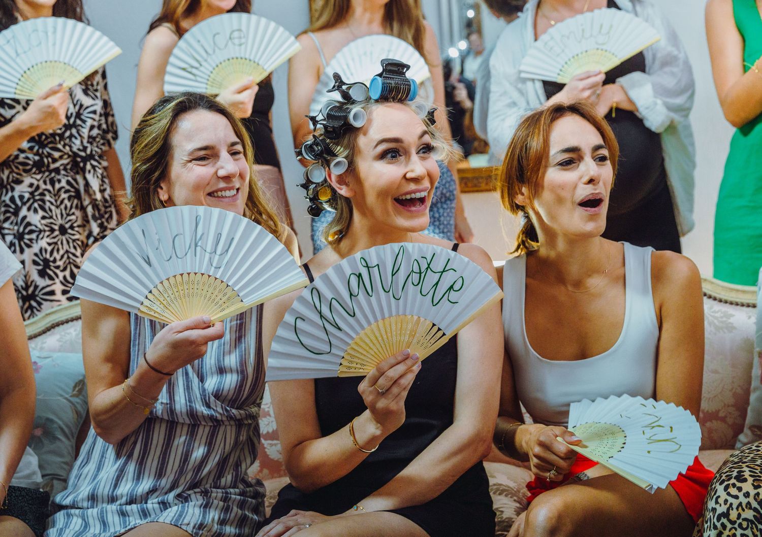 Group holding matching blue decorative hand fans while smiling at an outdoor event.