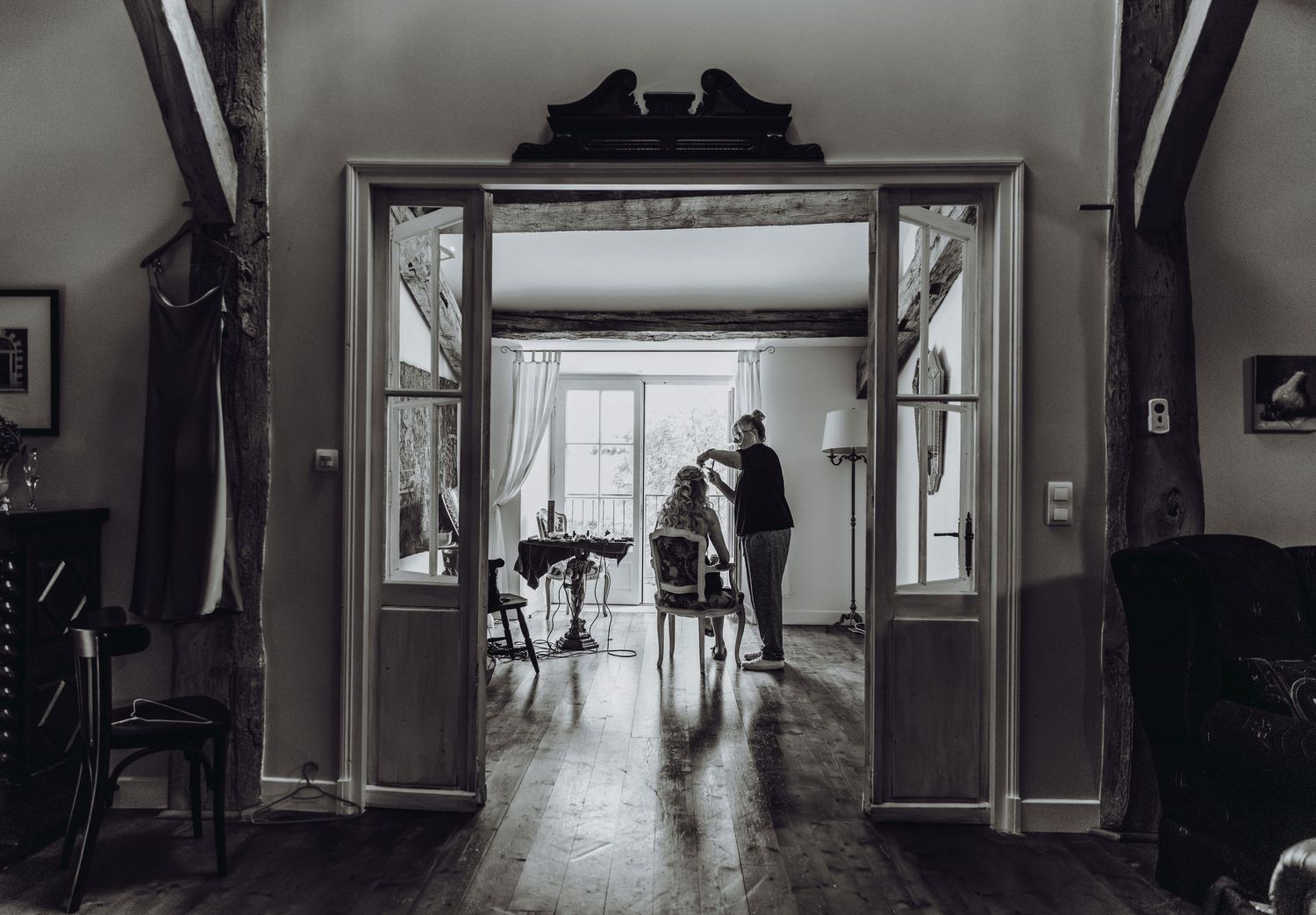 Black and white photograph showing a silhouette through an elegant doorway in a vintage-style interior.