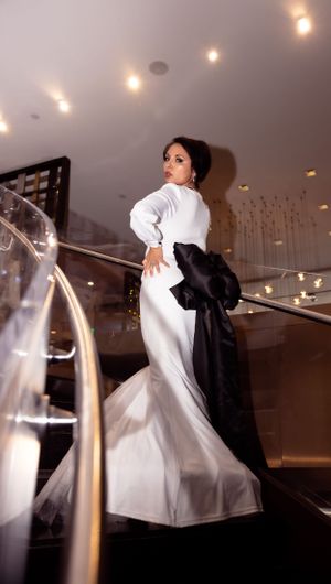 Dramatic staircase shot of person in flowing white gown with black wrap at formal venue.