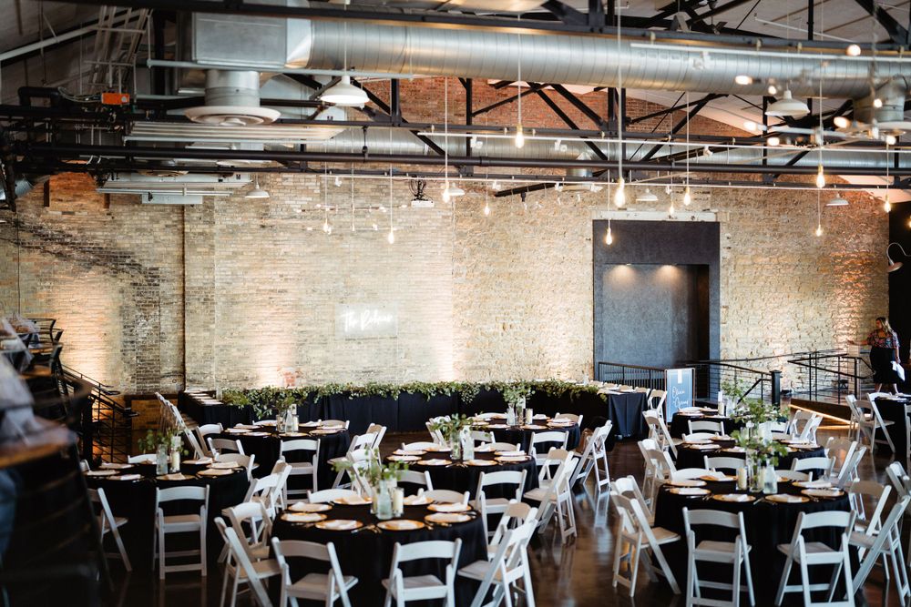 Industrial chic wedding venue with exposed brick walls and white chairs set up for reception.