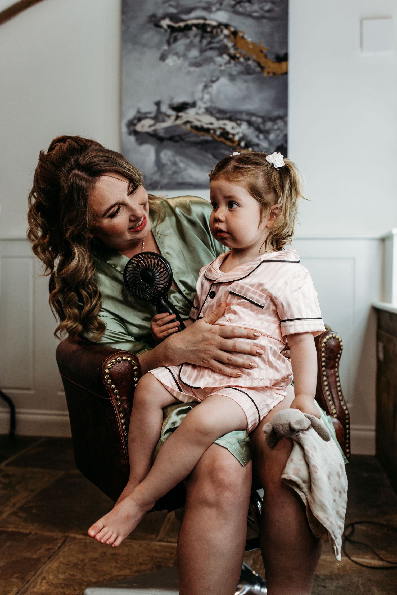 Tender moment between two people sitting in a leather chair while holding a fan.