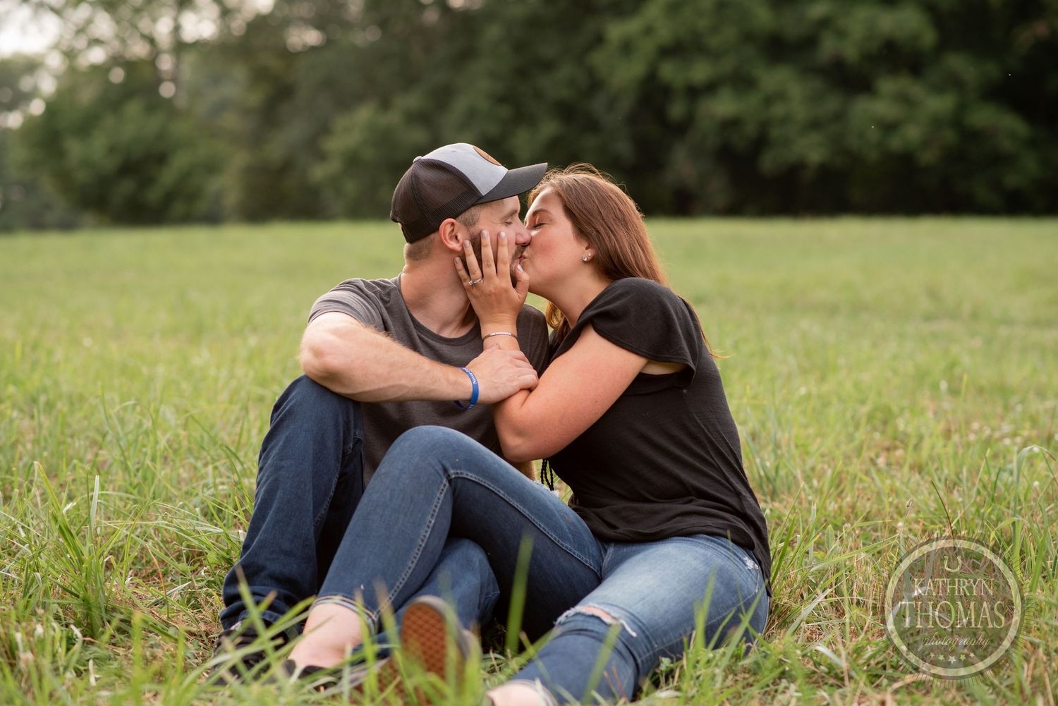 Romantic couple sitting close together on grass during outdoor photo session.