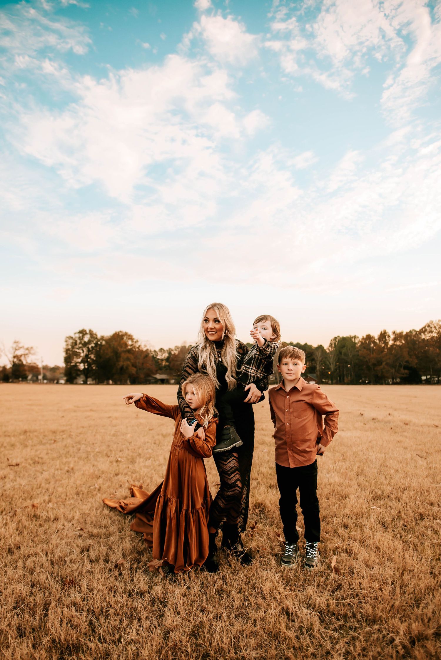 A group poses together in an autumn field under a bright blue sky.