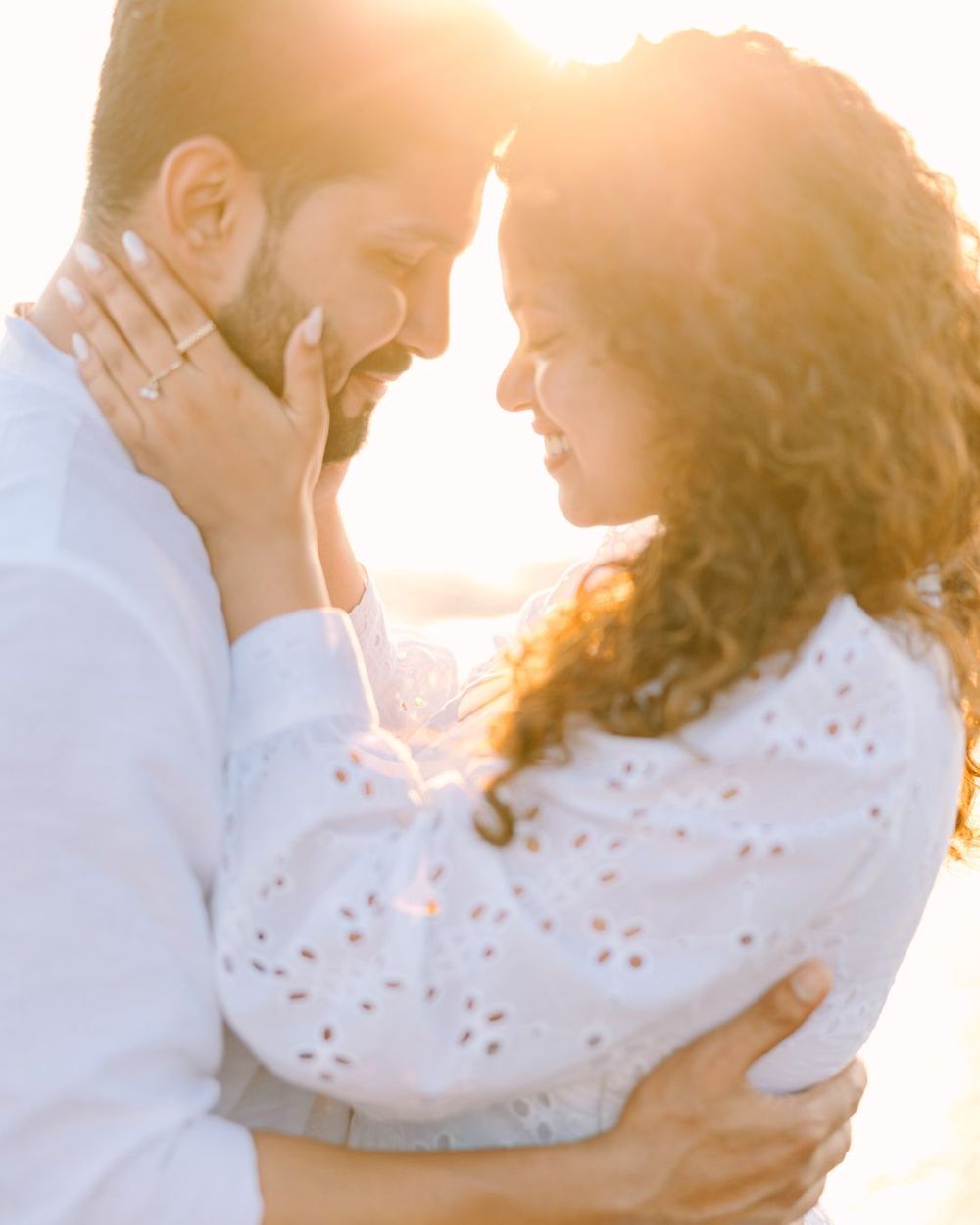 Tender embraces between couple on beach during golden hour photoshoot.