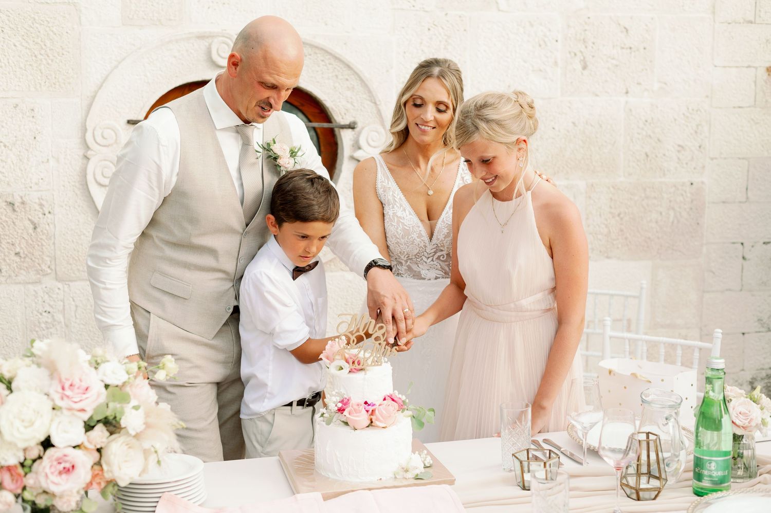 Family gathered around wedding cake during reception celebration.