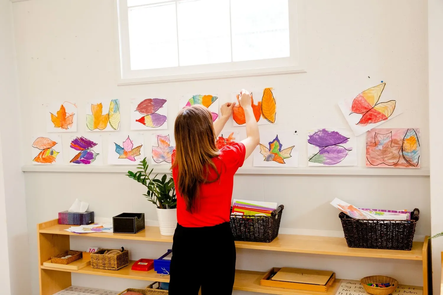 Colorful butterfly artwork decorates a classroom wall above wooden storage shelves.