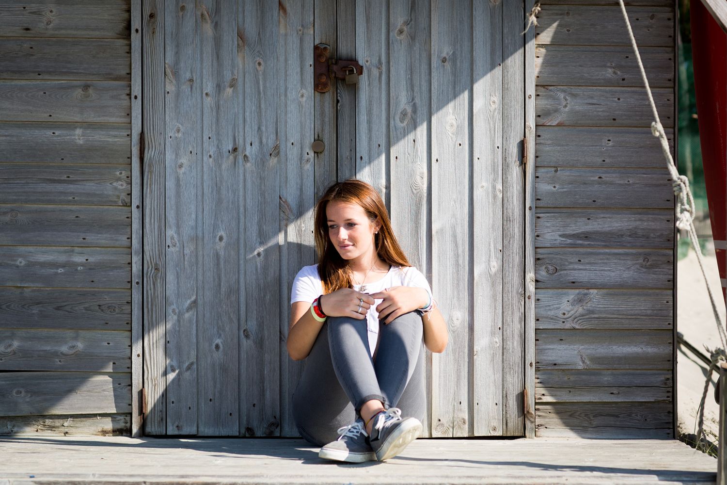 Person sitting on wooden steps of beach hut in athletic wear during business branding photoshoot