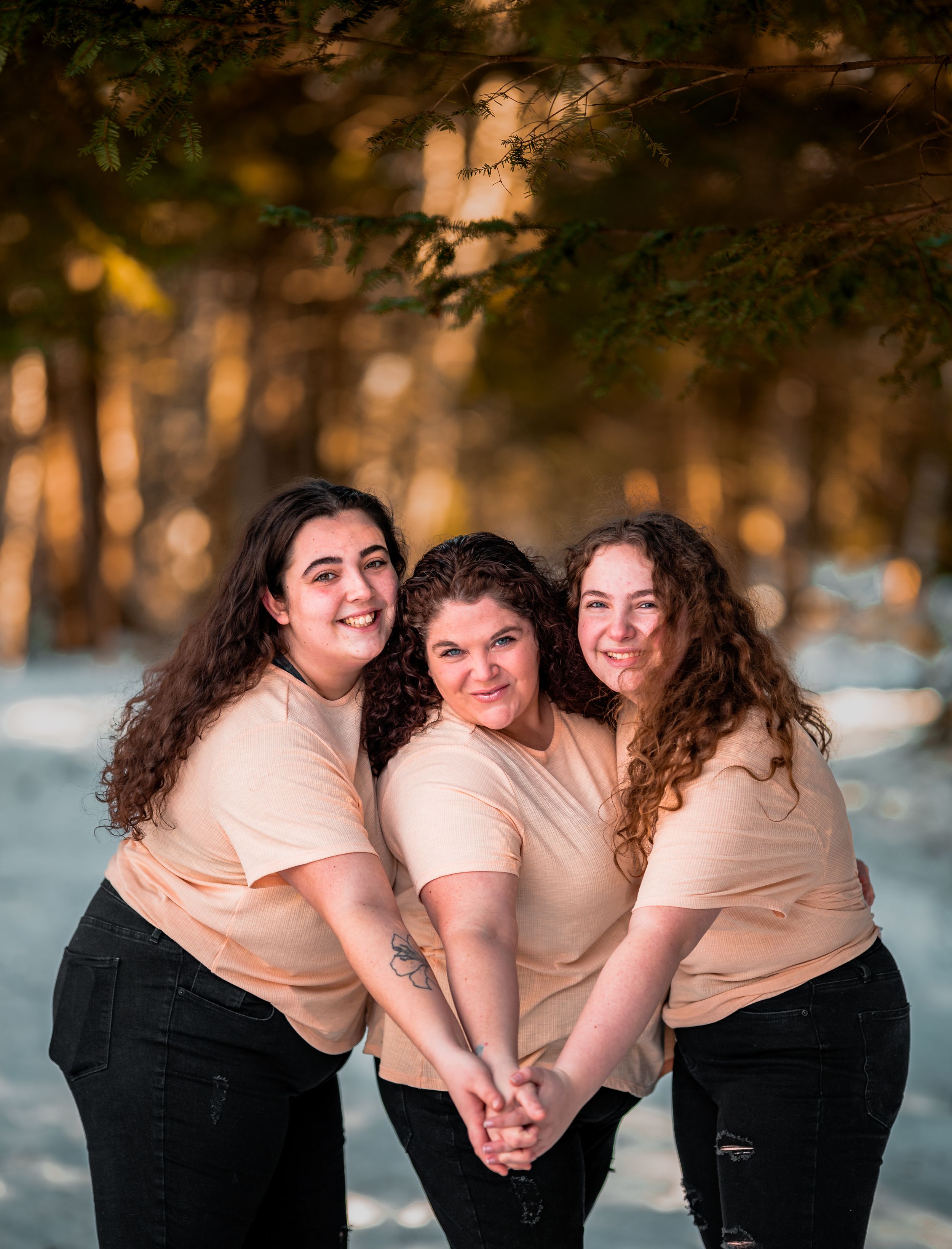 Friends in matching outfits share laughs during a winter photoshoot in the snow.
