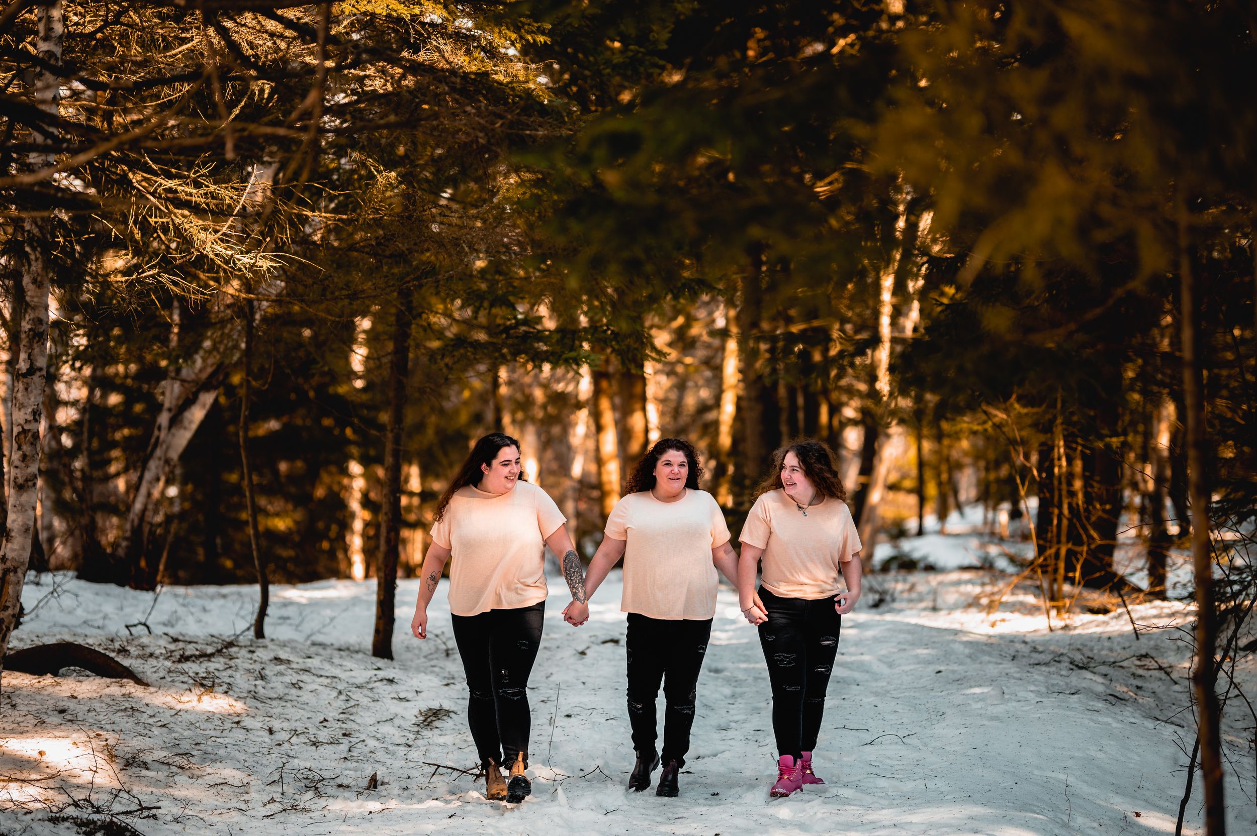 Group walking together through a snowy forest path at sunset.