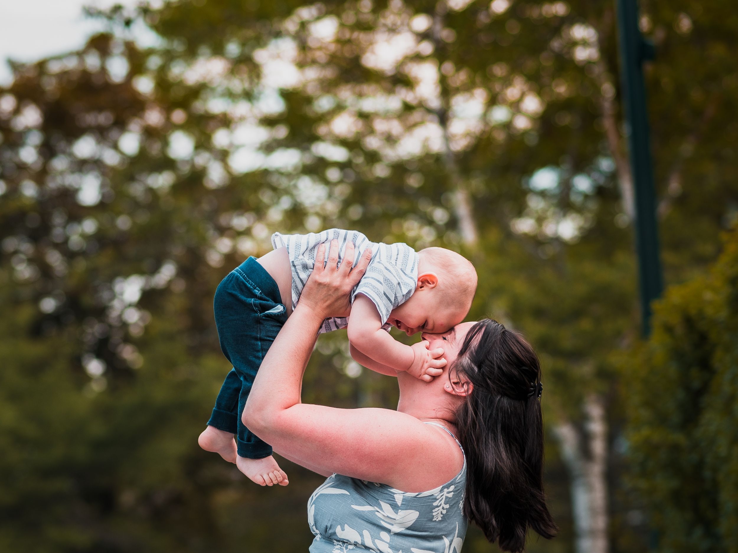 Playful outdoor parent-child moment captured in a natural park setting.